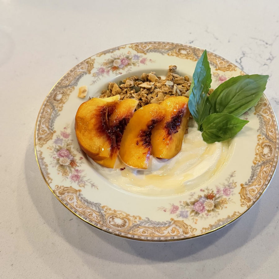 grilled peaches with yogurt, granola, and basil on a vintage plate